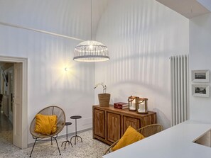 Relax in this serene space with a large pendant light, a comfortable sofa, and a vase of fresh flowers.