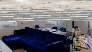 A modern hotel room with a blue sofa, a dining table, and a small kitchen area. - Poerio 98 Luxury Apartment (Naples)