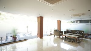 A modern lobby with a glass partition, a sofa, a coffee table, and potted plants. - Udman by Ferns N Petals Gurugram (Gurugram)
