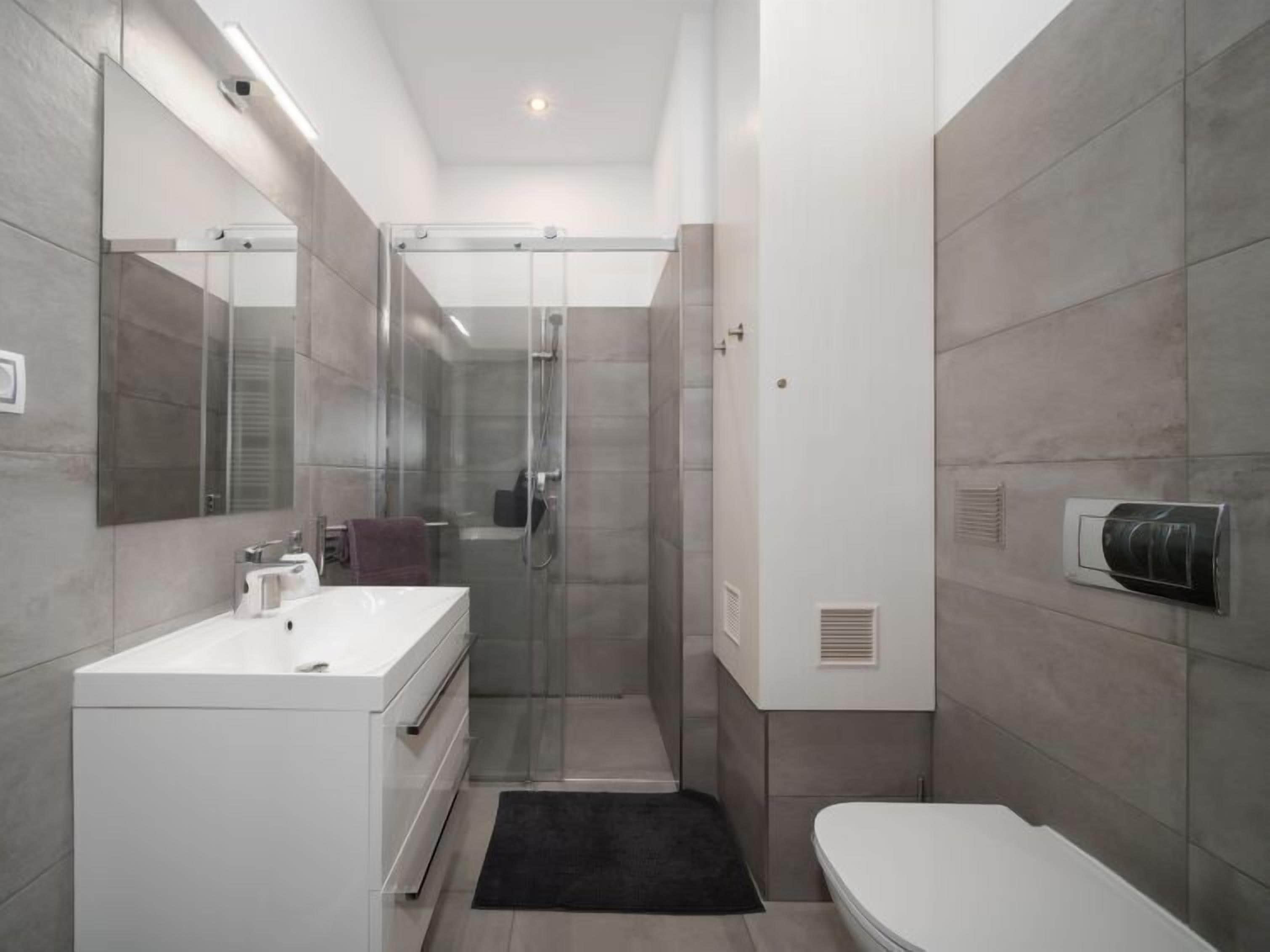 A modern bathroom with a glass shower enclosure, a white sink, and a toilet.