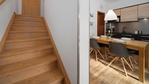 A modern kitchen with wooden cabinets, a dining table, and chairs.