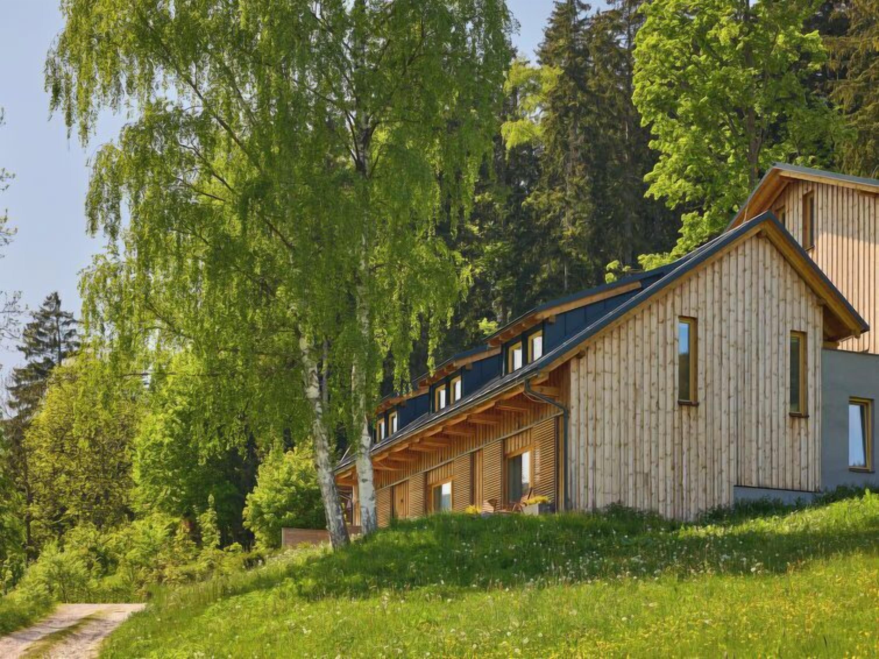 A wooden cabin with a sloped roof, large windows, and a covered porch area.