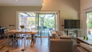 Ein modernes Wohnzimmer mit einem Holzesstisch, bequemen Sitzgelegenheiten, einem Flachbildfernseher und einer Steinwand.