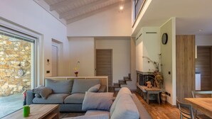 Ein modernes Wohnzimmer mit einem grauen Ecksofa, einem Holztisch und einer Steinwand.