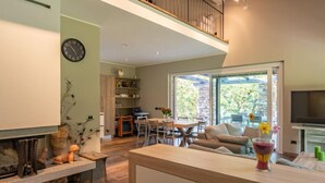 Ein modernes Wohnzimmer mit Kamin, Essbereich und Balkon mit Blick.