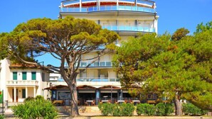 Un hôtel à plusieurs étages, doté d’une section centrale circulaire, de balcons et d’un espace restaurant avec des places assises en plein air.