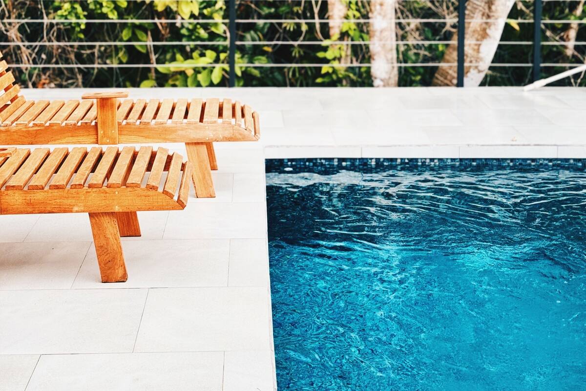 A pool area with wooden loungers and a clear blue pool.
