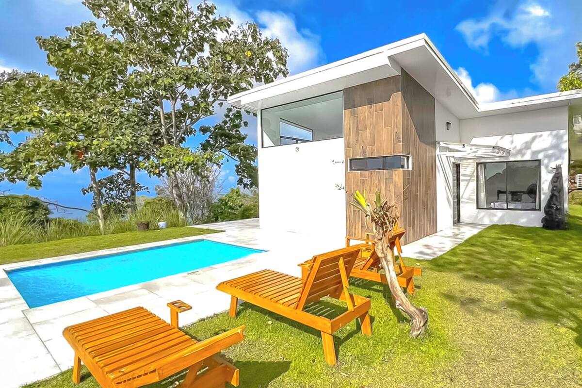 A modern house with a swimming pool, wooden deck, and outdoor seating.