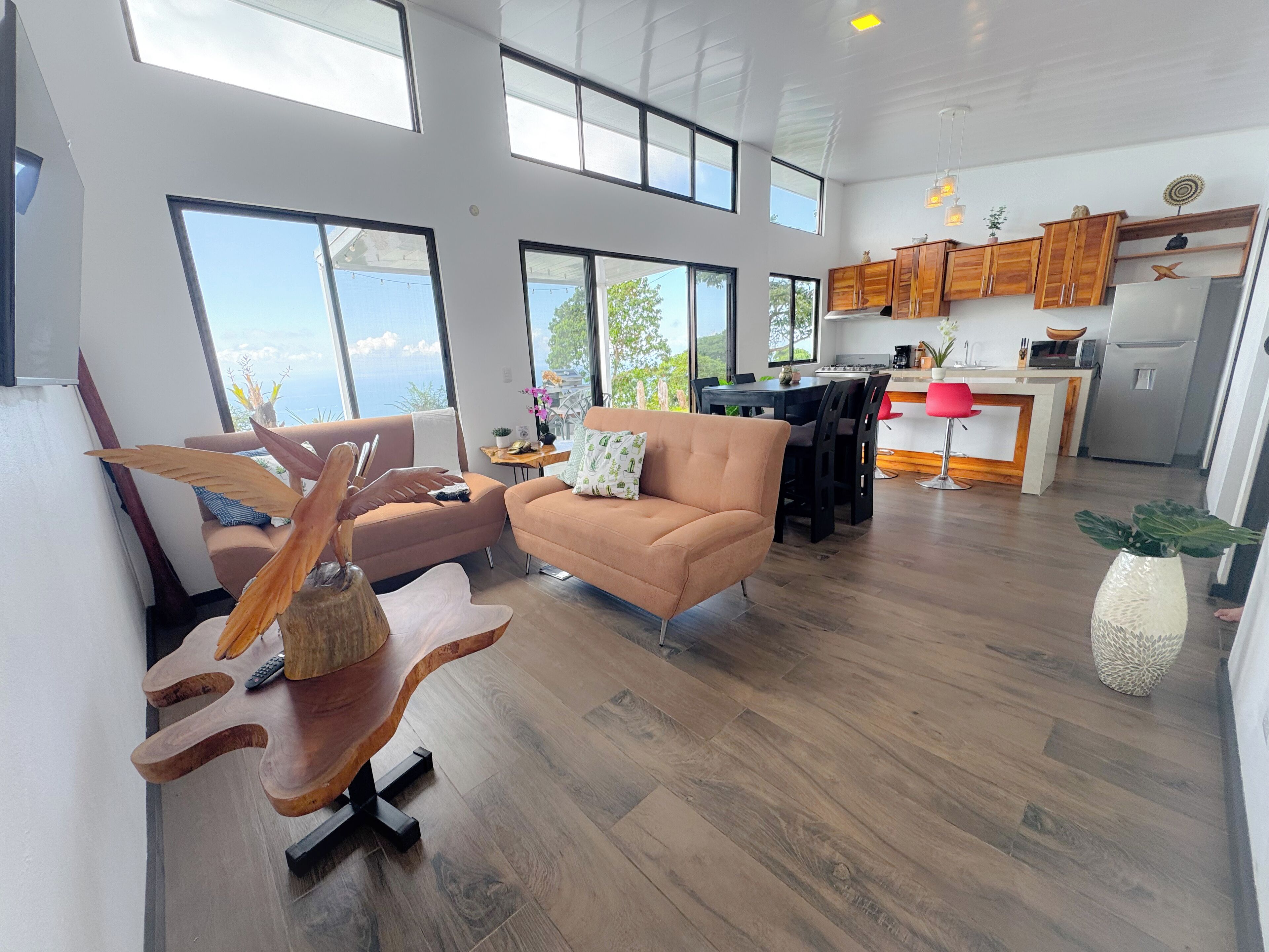 A spacious living area with a modern kitchen, large windows, and a view of the outdoors.