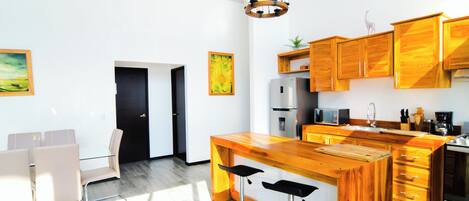 Una cocina moderna con armarios de madera, una isla central con taburetes de bar, un refrigerador y un microondas.