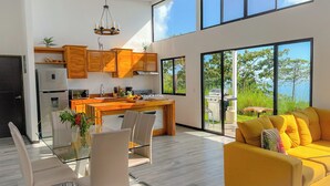 Una cocina moderna con armarios de madera, un comedor con mesa de vidrio y un sofá amarillo.