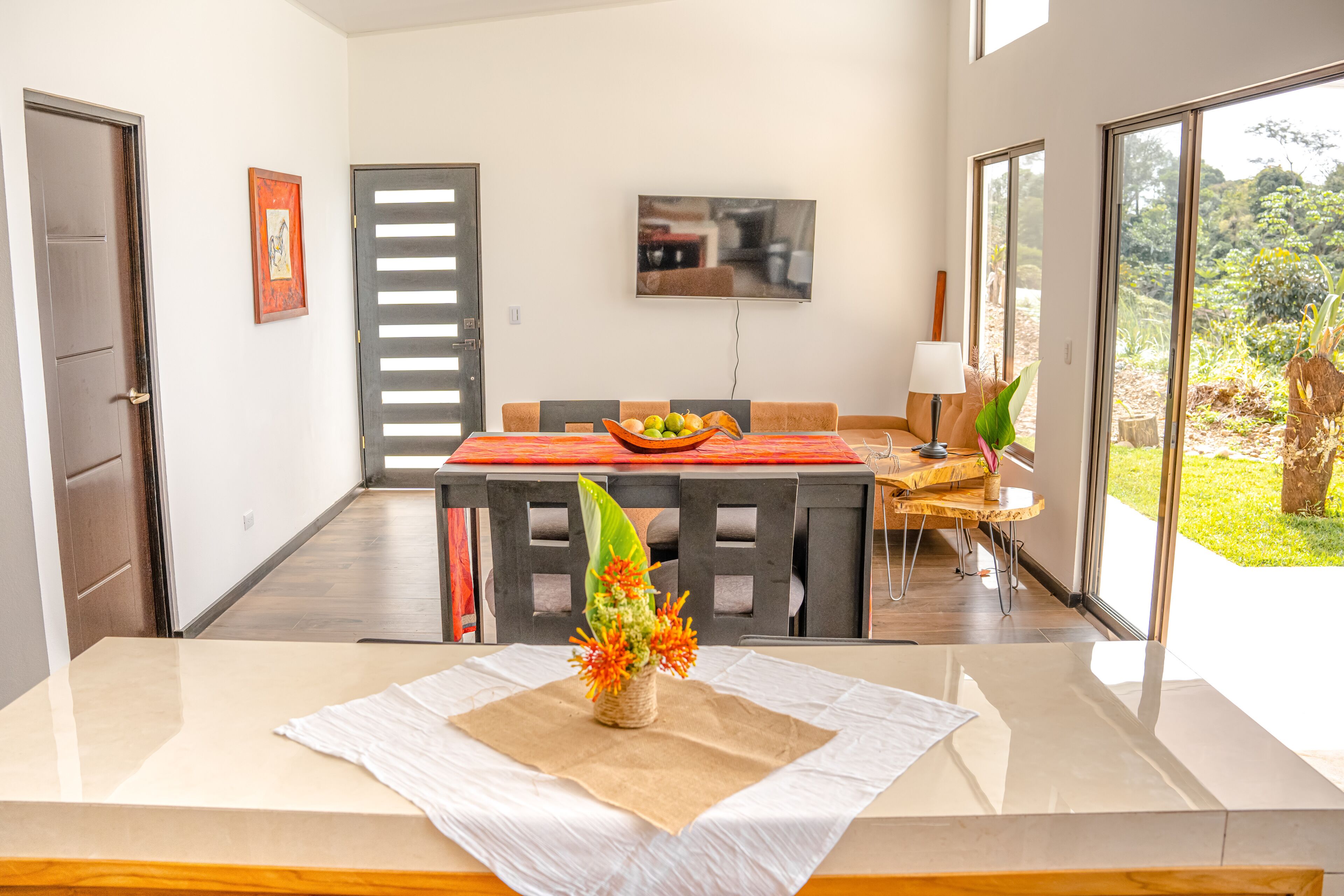 A modern dining area with a wooden table, chairs, and a central vase with flowers.