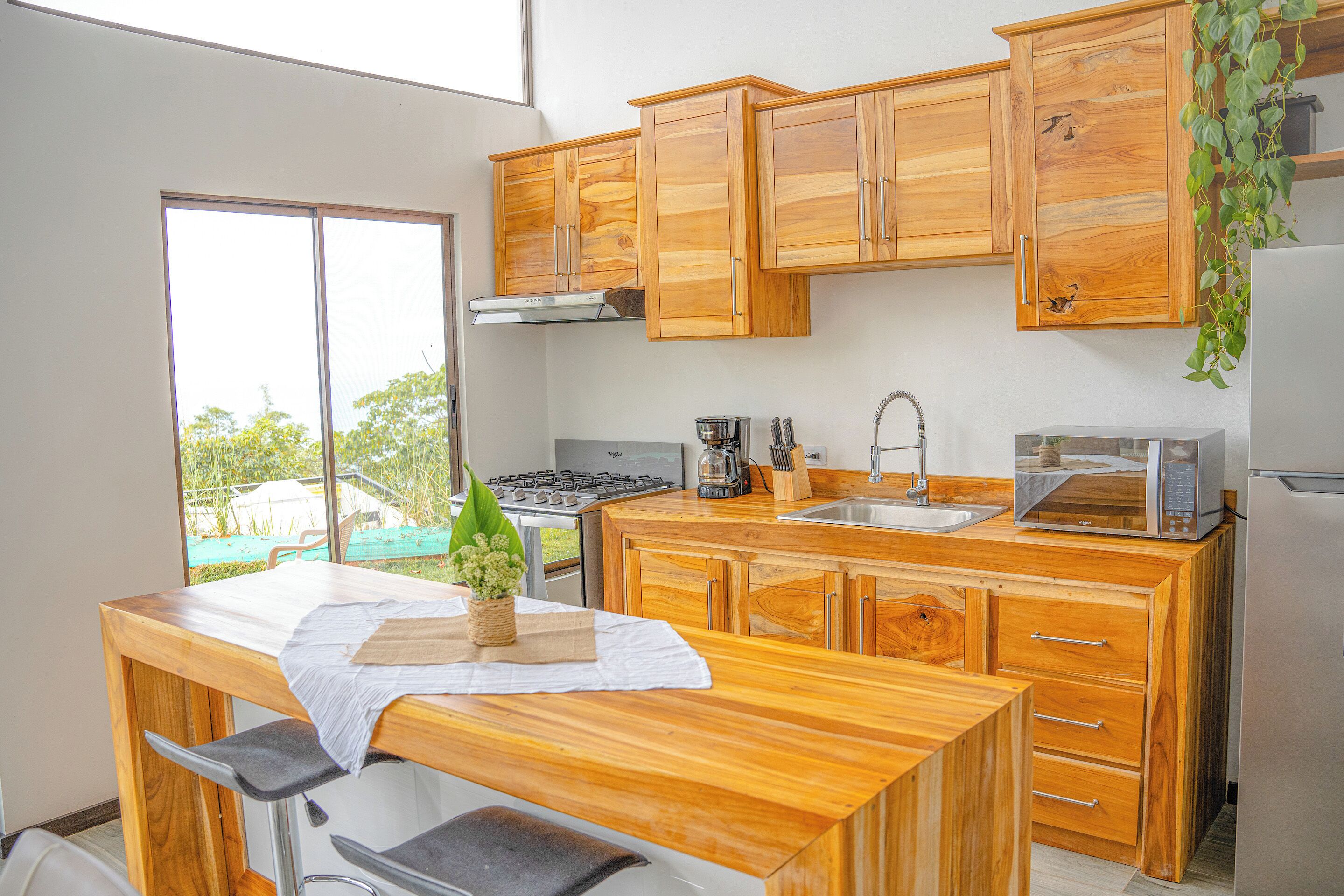 A modern kitchen with wooden cabinets, a gas stove, a sink, and a microwave.