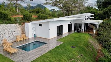 Una casa moderna con piscina, terraza de madera y zona de patio techada.