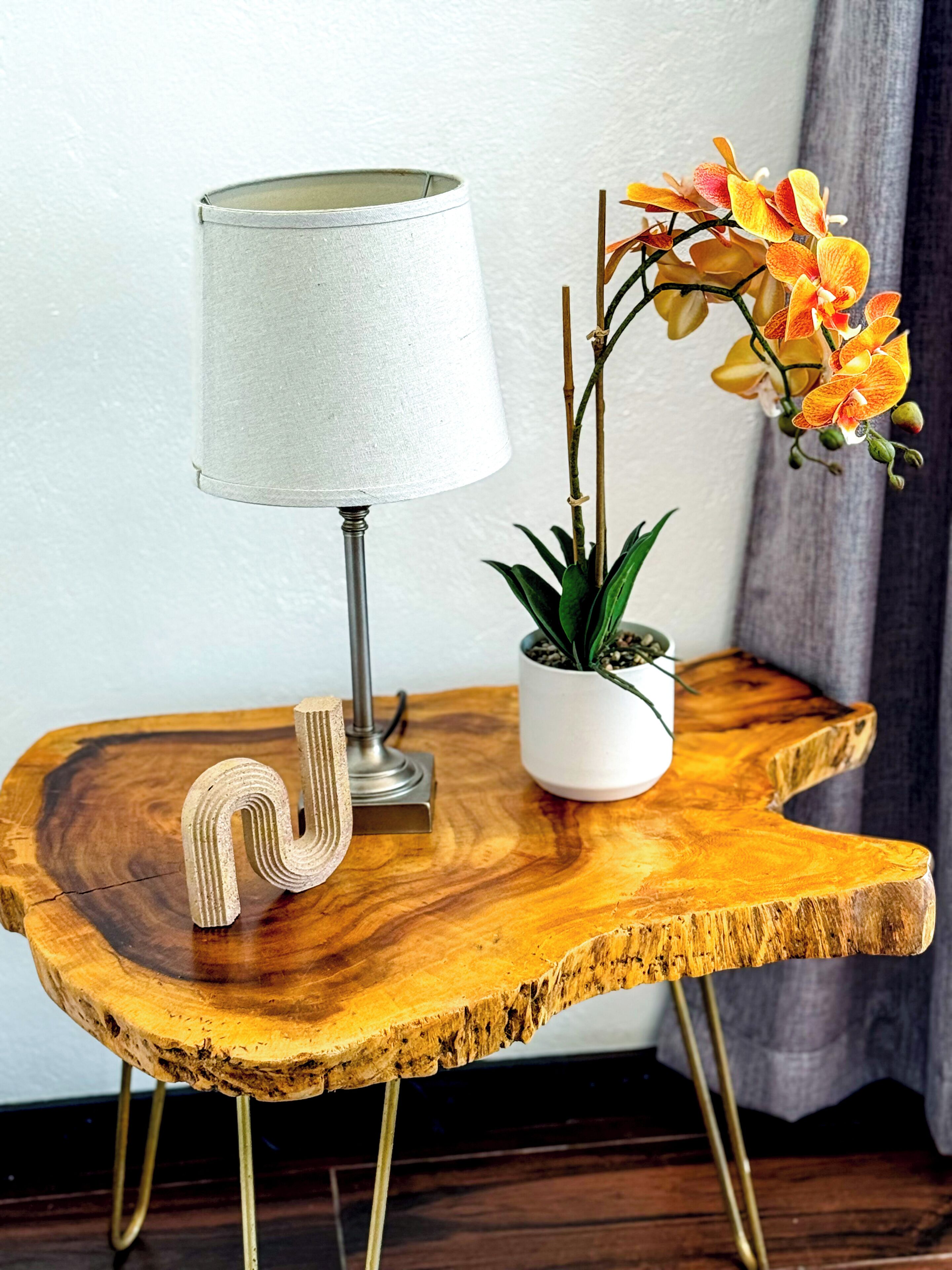 Una mesita de madera con una lámpara y una planta en maceta.