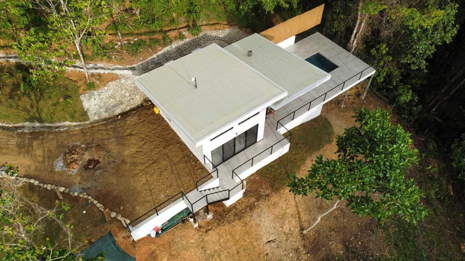 Ein modernes Haus mit flachem Dach, einer kleinen Terrasse und einer Treppe zum Haupteingang.