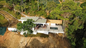 A modern house with a flat roof, a covered patio, and a swimming pool.