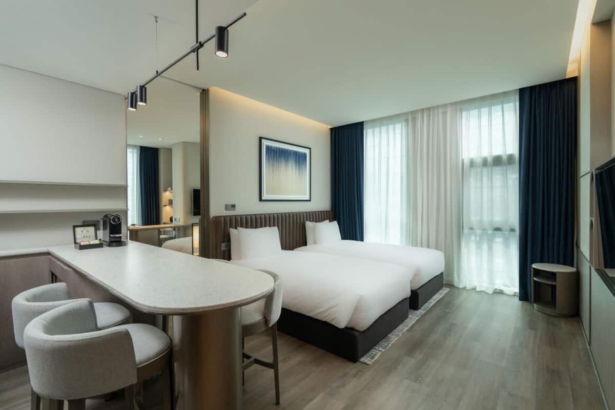 A modern hotel room with a large bed, a desk, and two chairs.