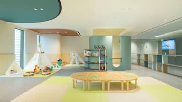 A modern children's play area with a tent, play table, and shelves with toys.
