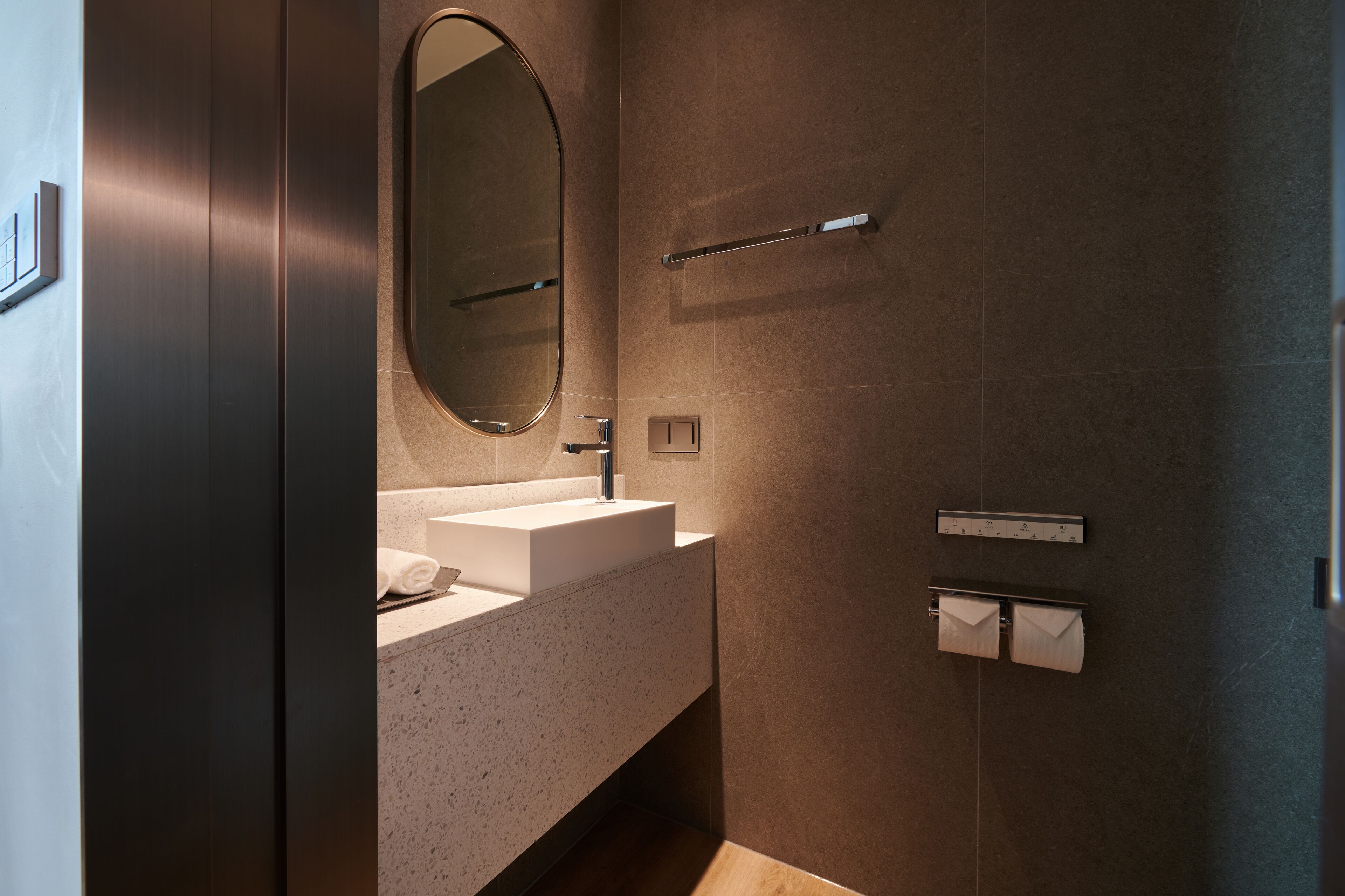 Un baño moderno con un lavabo rectangular, un espejo grande y un perchero para toallas.