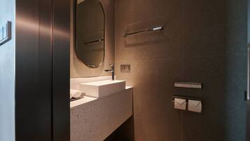 Un baño moderno con un lavabo rectangular, un espejo grande y un perchero para toallas.