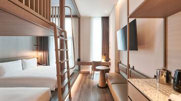 A hotel room with two beds, a desk, a chair, a TV, and a coffee maker.