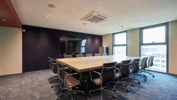 A conference room with a large table, chairs, and a view of the city through large windows.