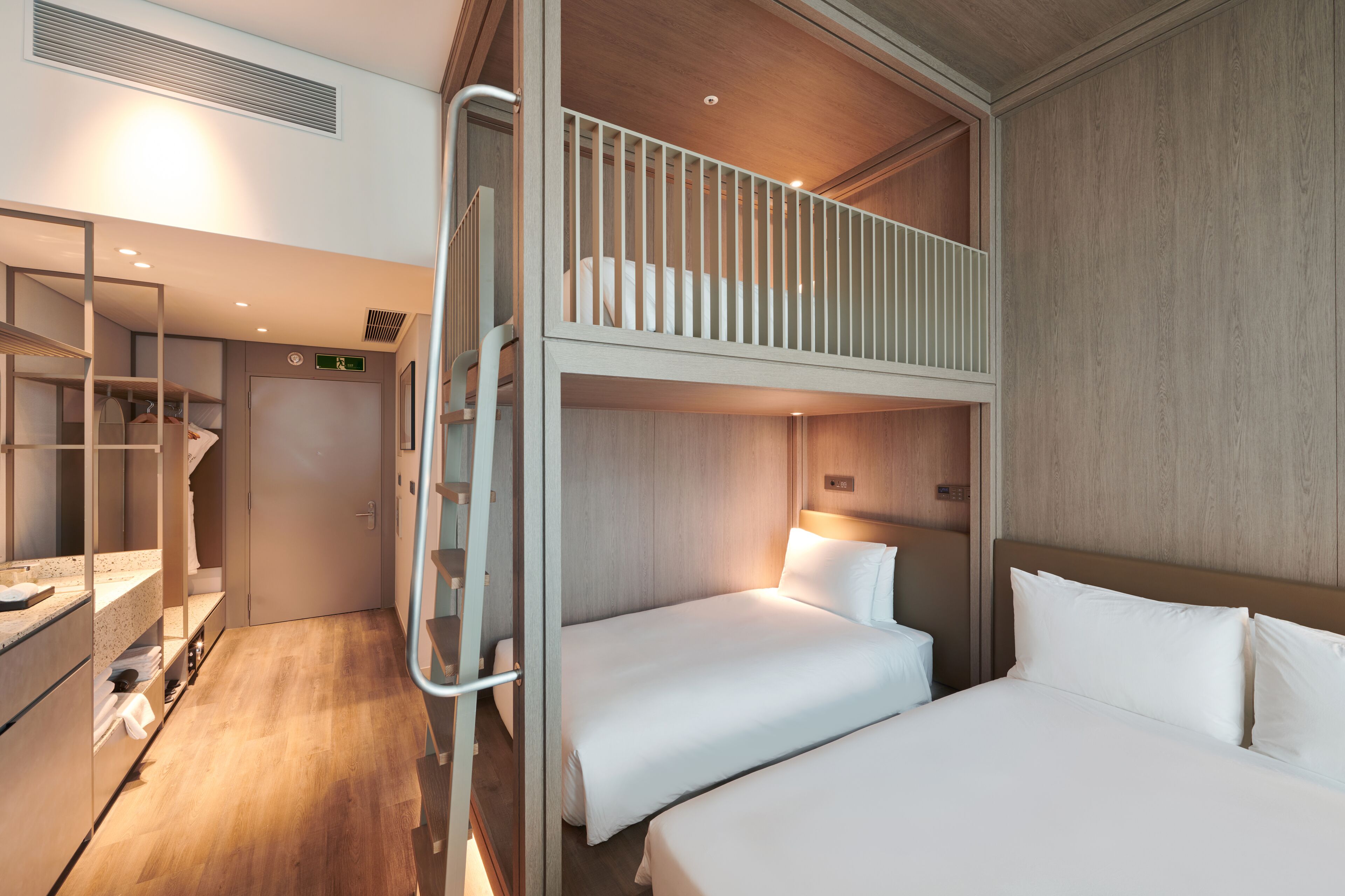 Una habitación de hotel con una litera, un escritorio con una silla y un armario.