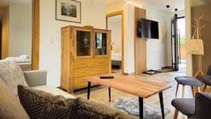 A modern living room with a sofa, a wooden cabinet, a TV, and a dining area.