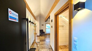 A hallway with a sign for 'interhome' on the left, a chair in the middle, and a staircase on the right. - Home Fuchsbau by Interhome (See)