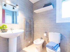Une salle de bain moderne avec un lavabo blanc, un bidet et des toilettes.