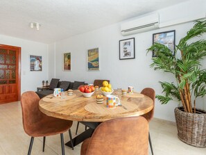 A dining area with a round wooden table, brown upholstered chairs, and a potted plant.