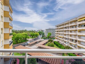 Un edificio residencial de varios pisos con balcones, un patio central con árboles y vista a la calle.