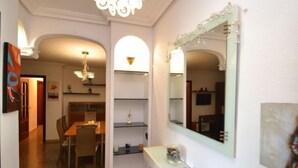 Un couloir comprenant un coin repas, un miroir et une petite étagère ornée d’objets décoratifs.