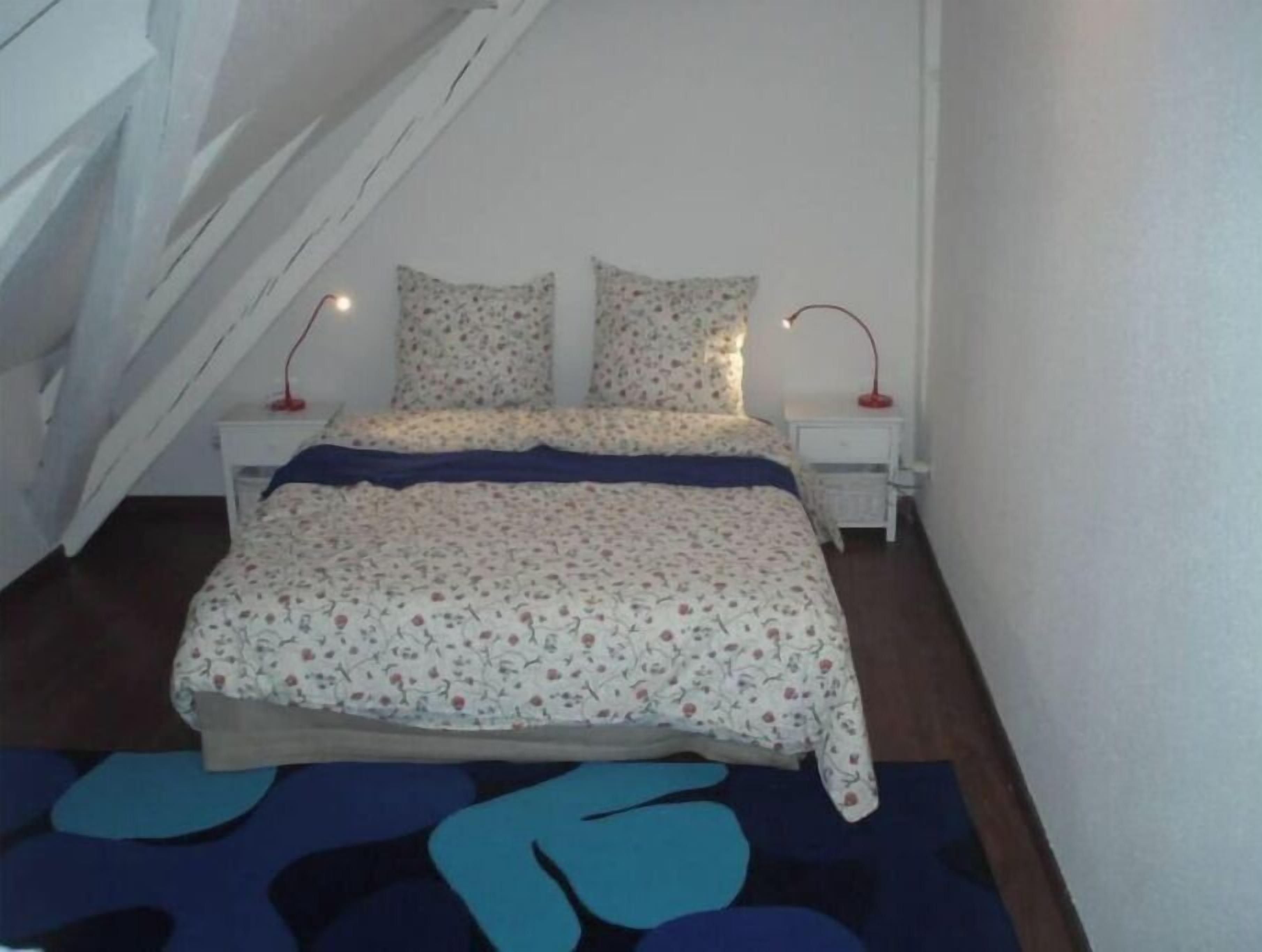 A bedroom with a bed, two bedside tables, and a nightstand.
