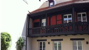 Ein zweistöckiges Gebäude mit Balkon, Fenstern und einem kleinen Garten.