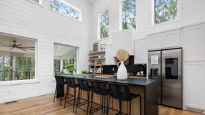 A modern kitchen with a large island, stainless steel appliances, and a view of the outdoors.