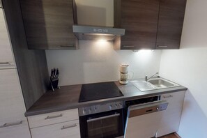A compact kitchen with a stove, sink, and integrated dishwasher. - Holiday Home Bodensdorf near Ski & Lake (Bodensdorf am Ossiachersee)