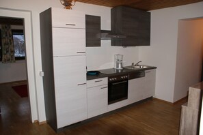 A modern kitchen with white cabinetry, a built-in oven, a coffee maker, and a sink.