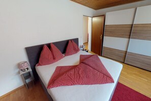 Une chambre d’hôtel avec un lit, des oreillers, une table de chevet, une lampe et une armoire.