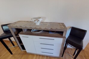 A small wooden desk with a white drawer unit, two black chairs, and a decorative ceramic pitcher on top. - Holiday Home Bodensdorf near Ski & Lake (Bodensdorf am Ossiachersee)