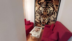 Een kamer met een grote tijger muurschildering, rode banken en een kleine witte salontafel.