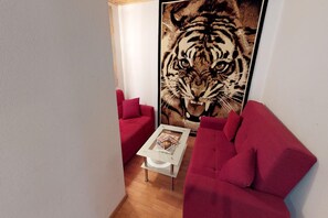 A room with a red sofa, a glass coffee table, and a large tiger print artwork on the wall. - Holiday Home Bodensdorf near Ski & Lake (Bodensdorf am Ossiachersee)