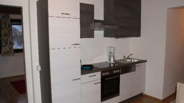 A compact kitchen with white cabinets, a black stove, and a coffee maker. - Holiday Home Bodensdorf near Gerlitzen Ski Area (Bodensdorf am Ossiachersee)