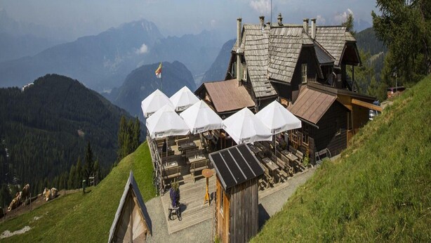 A mountain lodge with wooden cabins, outdoor seating, and a scenic mountain backdrop.