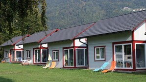 Eine Reihe von Holzhütten mit großen Fenstern und roter Umrandung, vor einer Bergkulisse.