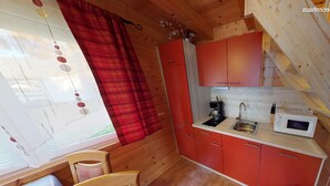 A compact kitchen with red cabinets, a sink, and a microwave.