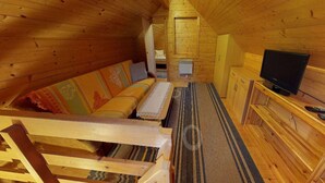 A wooden cabin interior with a sofa, a television, and a small cabinet. - Holiday Home Bodensdorf near Gerlitzen Ski Area (Bodensdorf am Ossiachersee)