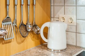 A kitchen counter with a white electric kettle and various kitchen utensils hanging on the wall. - Holiday apartment in Kaltenbach (Kaltenbach)