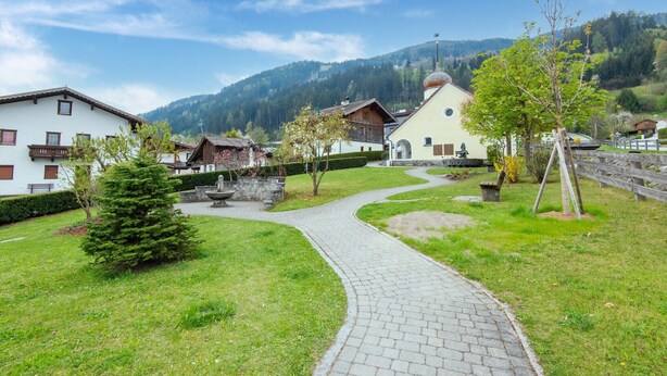 A paved pathway leading to traditional buildings with a mountainous backdrop. - Holiday apartment in Kaltenbach (Kaltenbach)